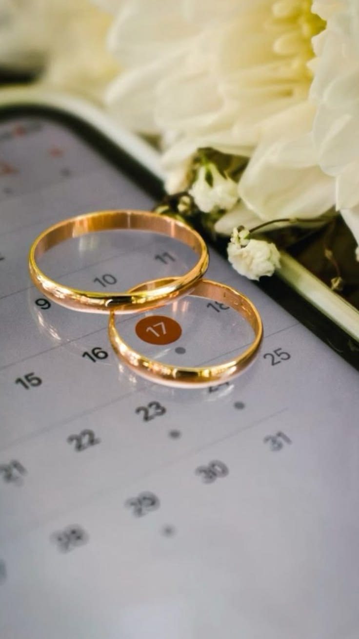 Rings resting on a save-the-date calendar, dimly lit